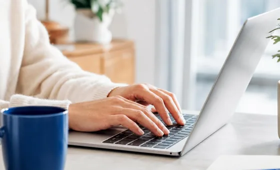Hands typing carefully on a laptop.